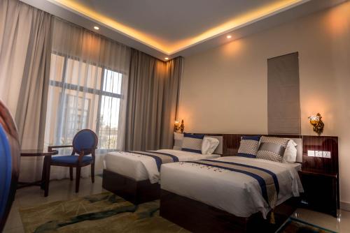 una camera d'albergo con due letti e una sedia di Asmara Hotel a Lusaka