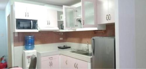 a kitchen with white cabinets and a stainless steel refrigerator at ONE OASIS a1 SM MALL DAVAO FREE POOL WIFI in Davao City