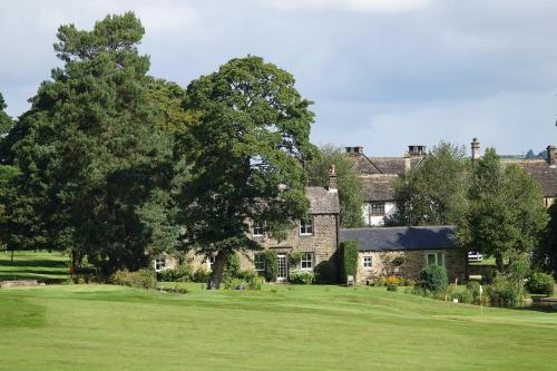 a large stone house with a green yard at Woodsome Hall Golf Club Cottage on the Course in Fenay Bridge