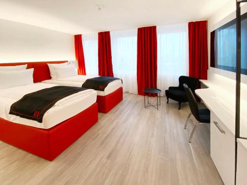 two beds in a hotel room with red curtains at DORMERO Hotel Hersbruck in Hersbruck