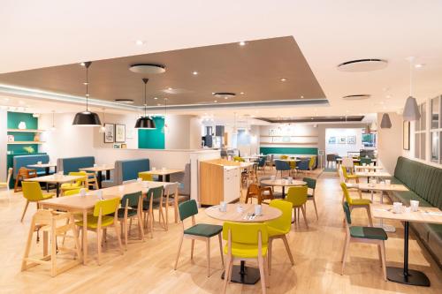 a dining room with tables and yellow chairs at Holiday Inn Southampton Eastleigh by IHG in Southampton
