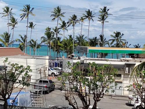 a view of a building with palm trees and the ocean at APARTAMENTO EM LOCAL PRIVILEGIADO in Maceió