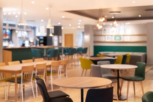 a restaurant with tables and chairs and a bar at Holiday Inn Southampton Eastleigh by IHG in Southampton