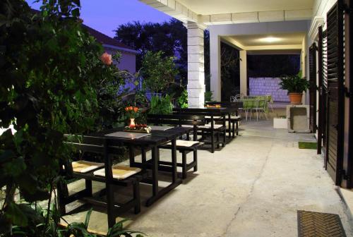 une rangée de tables et de bancs sur un patio dans l'établissement Apartments Magda, à Cavtat