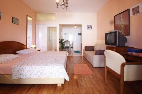 a bedroom with a bed and a couch and a tv at Apartments Magda in Cavtat