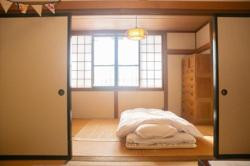 a bedroom with a bed in a room with a window at Minpaku AMBO - Friendly share house - in Kazuno