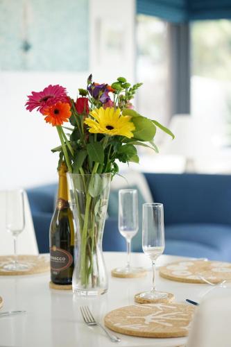 a table with a vase of flowers and a bottle of wine at Seagrass - Ventnor in Ventnor