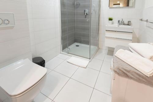 a white bathroom with a shower and a toilet at VacationClub – 5 Mórz Sianożęty Apartament 1J/2 in Sianozety
