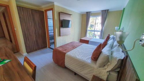 um quarto de hotel com uma cama e uma televisão em Pousada Reserva do Sahy em Mangaratiba