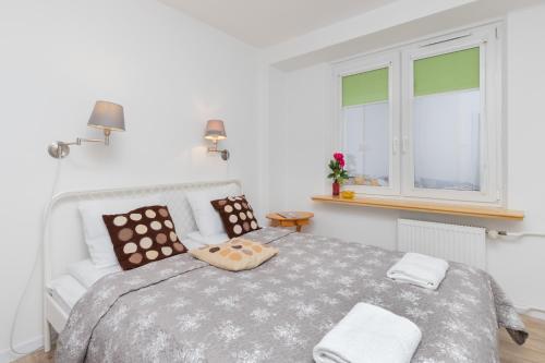 a white bedroom with a bed with pillows and a window at City Center Apartment Gdynia by Renters in Gdynia