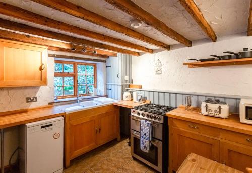La cuisine est équipée de placards en bois et d'un four avec plaques de cuisson. dans l'établissement Bay Cottage By The Sea in Broadstairs., à Broadstairs