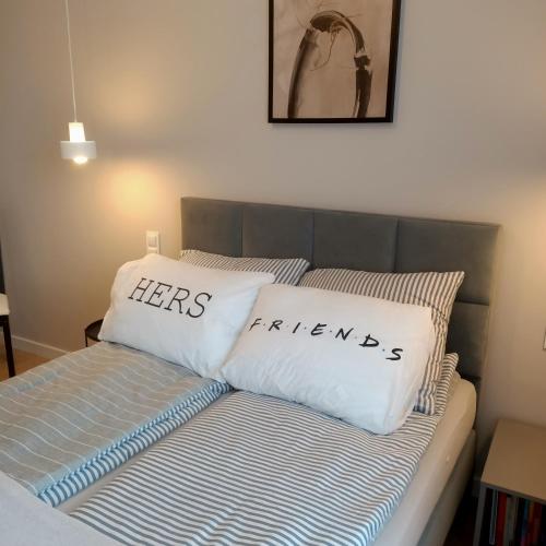a bed with two pillows with the words hers and friends at Apartament PERŁA POŁUDNIA in Suwałki