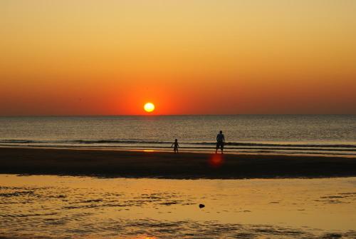 two people walking on the beach at sunset at Boulevard Hotel Scheveningen in Scheveningen