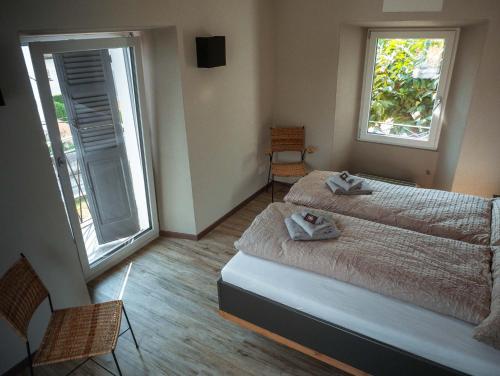 a bedroom with two beds and two windows at Stalder Meat & Bed in Muralto