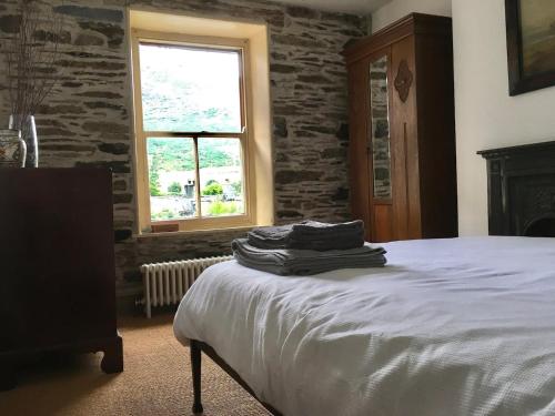 a bedroom with a bed and a stone wall at Chapel Cottage in Machynlleth