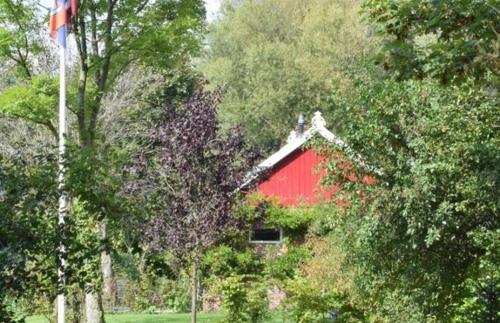 a red barn in the middle of some trees at Vakantiehuisje op de Rotmanshoeve in Kotten