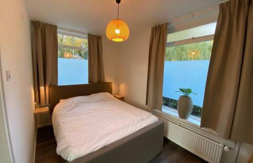 a bedroom with a white bed and two windows at Vakantiehuisje op de Rotmanshoeve in Kotten