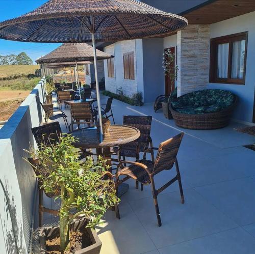 a patio with a table and chairs and an umbrella at Refúgio dos Coiotes in Cambara do Sul