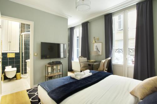 une chambre avec un grand lit et une télévision dans l'établissement Studio Opéra by Studio prestige, à Paris