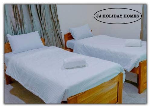 two beds with white sheets in a room at JJ Holiday Homes in Canaguinim