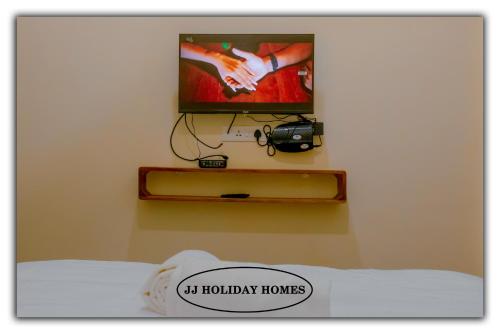 1 dormitorio con TV y 1 cama con cámara en JJ Holiday Homes en Canaguinim