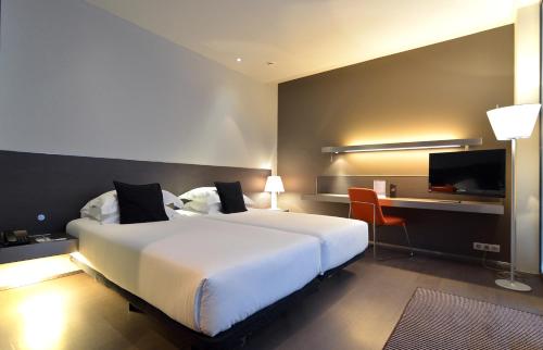 Habitación de hotel con cama blanca grande y escritorio. en Hotel Soho, en Barcelona