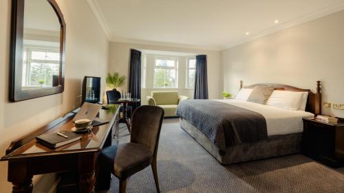 a hotel room with a bed and a desk and a mirror at Twin Trees Hotel & Leisure Club in Ballina