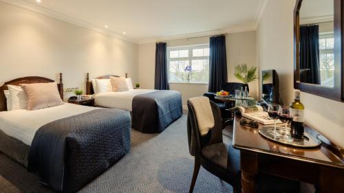 a hotel room with two beds and a desk at Twin Trees Hotel & Leisure Club in Ballina