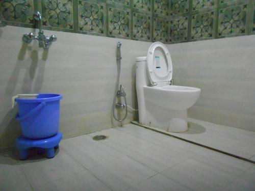 a bathroom with a toilet and a blue bucket at Nandan Kanan Auli Resort in Joshīmath