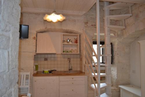 a kitchen with a staircase in a stone wall at Conversa De Amicis n°8 in Alberobello