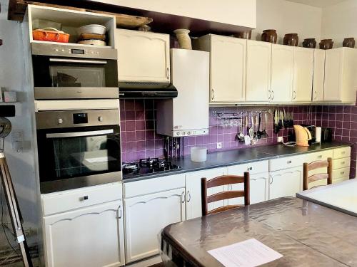 cocina con armarios blancos y encimera en Logements Un Coin de Bigorre - La Tournayaise - Canal plus, Netflix, Rmc Sport - Wifi Fibre, en Tournay