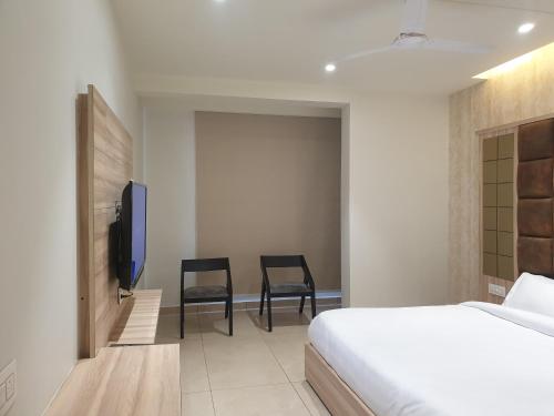 a bedroom with a bed and two chairs and a tv at Hotel Mark in Ambāla