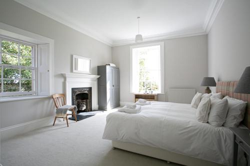 a white bedroom with a large bed and a fireplace at Auldhame House East Wing, Seacliff in North Berwick