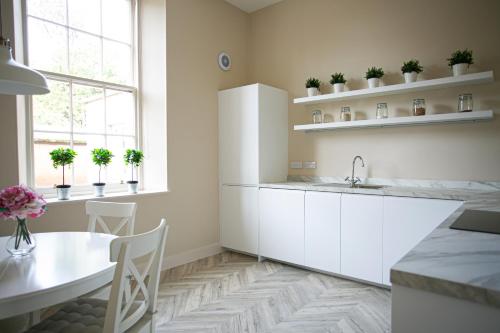 a kitchen with white cabinets and a table and a table and chairs at Auldhame House East Wing, Seacliff in North Berwick
