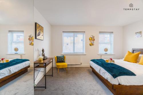 a bedroom with two beds and a table and a chair at STYLISH 4 BED FAMILY HOME AT MADEJSKI, READING UNIVERSITY in Reading