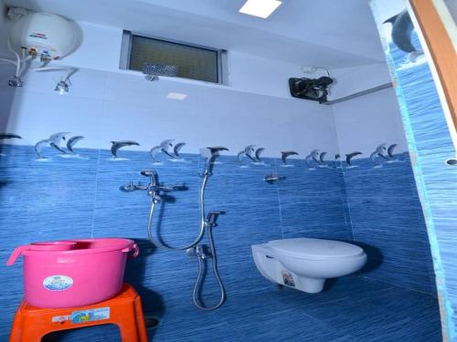 baño con aseo y ducha con delfines en la pared en The Tamarind Tree Hotel, en Port Blair