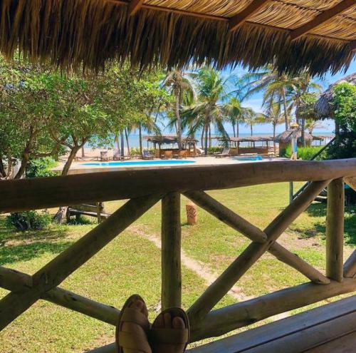a person sitting on a porch with their feet on a fence at Vila Itaqui in Luis Correia