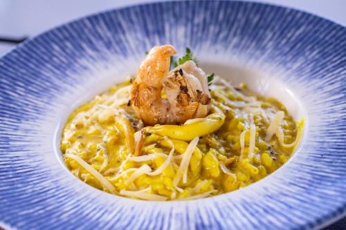 a blue bowl of food with shrimp and noodles at Vidam Hotel Aracaju - Transamerica Collection in Aracaju