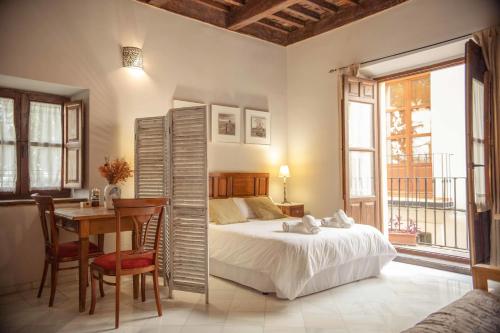 1 dormitorio con cama, mesa y escritorio en Alh Patio Apartamentos, en Granada