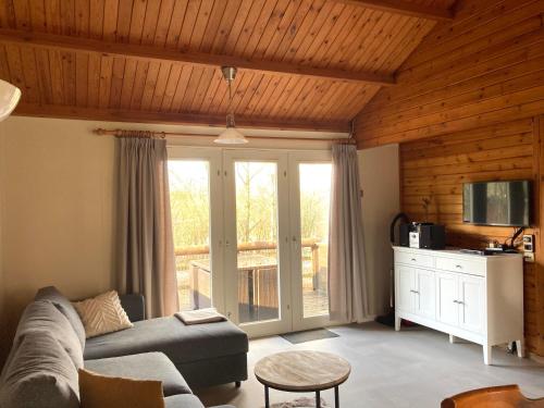 a living room with a couch and a sliding glass door at Familie Meys Chalets - Chalet 249 - La Boverie in Rendeux