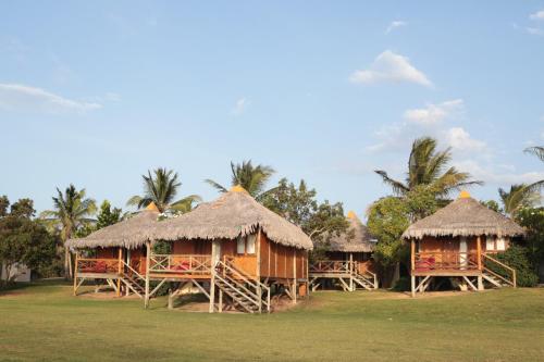 a group of huts with straw roofs and palm trees at Vila Itaqui in Luis Correia