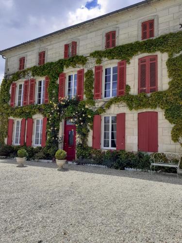 - un bâtiment avec des portes rouges et du lierre dans l'établissement Salle de réception et hébergements, à Rouffignac