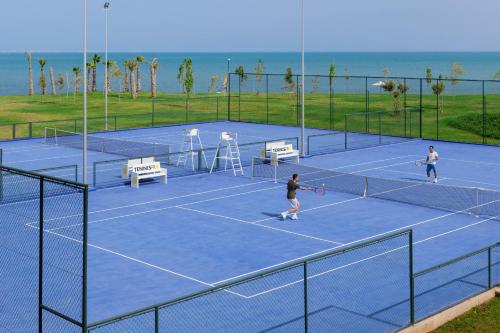 two people playing tennis on a tennis court at Marchica Lagoon Resort in Nador
