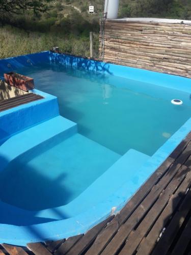 a blue swimming pool with a wooden deck at Mirador del Valle in Valle Hermoso