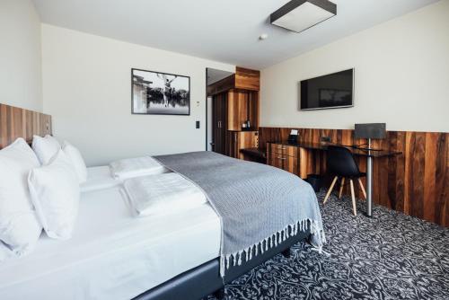 a bedroom with a bed with a desk and a television at Hotel Grauer Bär in Innsbruck