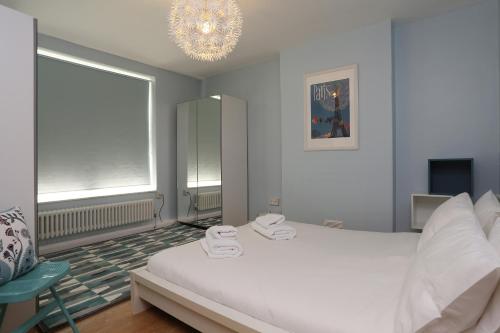 sypialnia z białym łóżkiem i żyrandolem w obiekcie Riverside Cutty Sark 2BD Retreat w Londynie