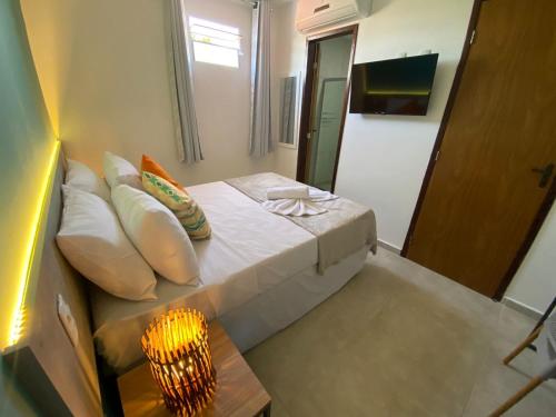 a small bedroom with a bed and a lamp at Mirante dos Corais in Porto De Galinhas