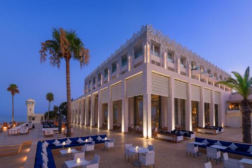 a building with tables and chairs and palm trees at Marchica Lagoon Resort in Nador