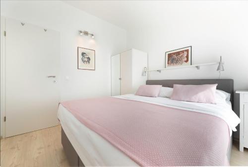 a white bedroom with a large bed with pink pillows at Apartment Arte Vrbnik in Vrbnik