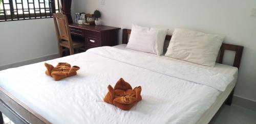 two stuffed animals sitting on top of a bed at Khmer House Guesthouse in Kep